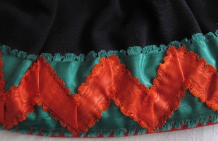 Skirt of the red costume, trimmed with red “Damest” and additionally decorated with a 6 cm wide green silk ribbon onto which a red ribbon is applied in a zig-zag line.